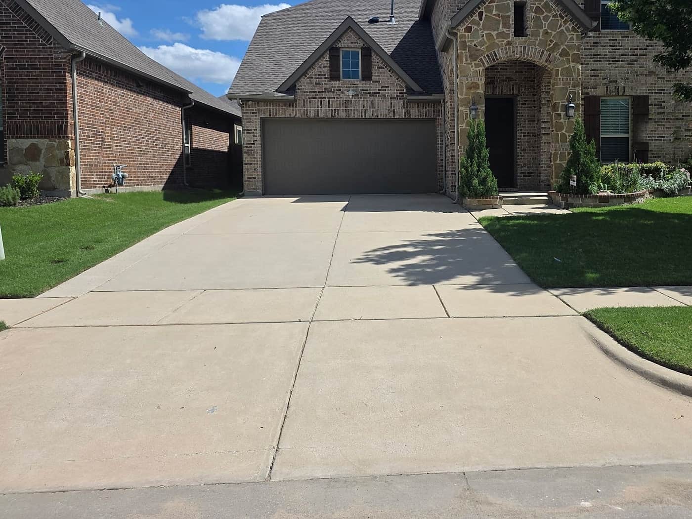 The same driveway after pressure washing, the concrete back to a clean, even pale grey across its whole width.